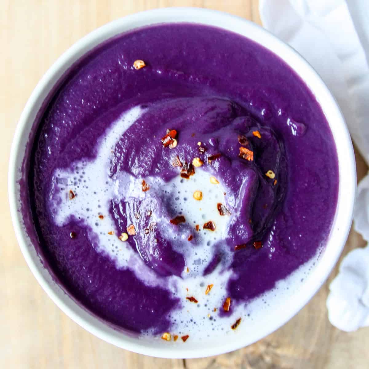 Bright purple red cabbage soup in a white bowl.